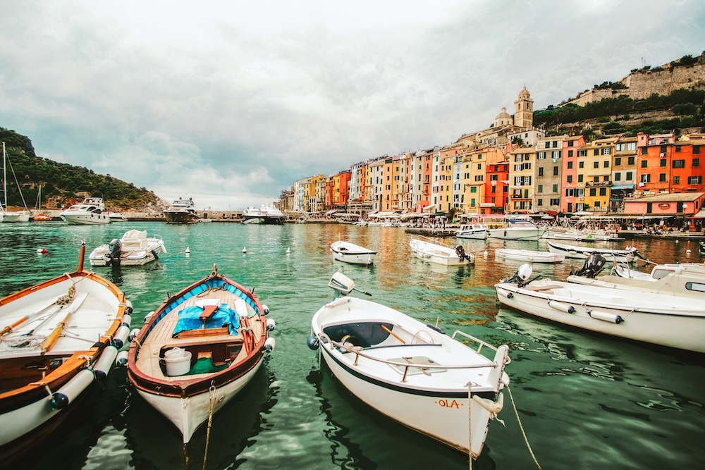 Bateau traditionnel amarré sur les eaux cristallines de Sicile, Italie, avec la côte méditerranéenne en arrière-plan sous un ciel bleu