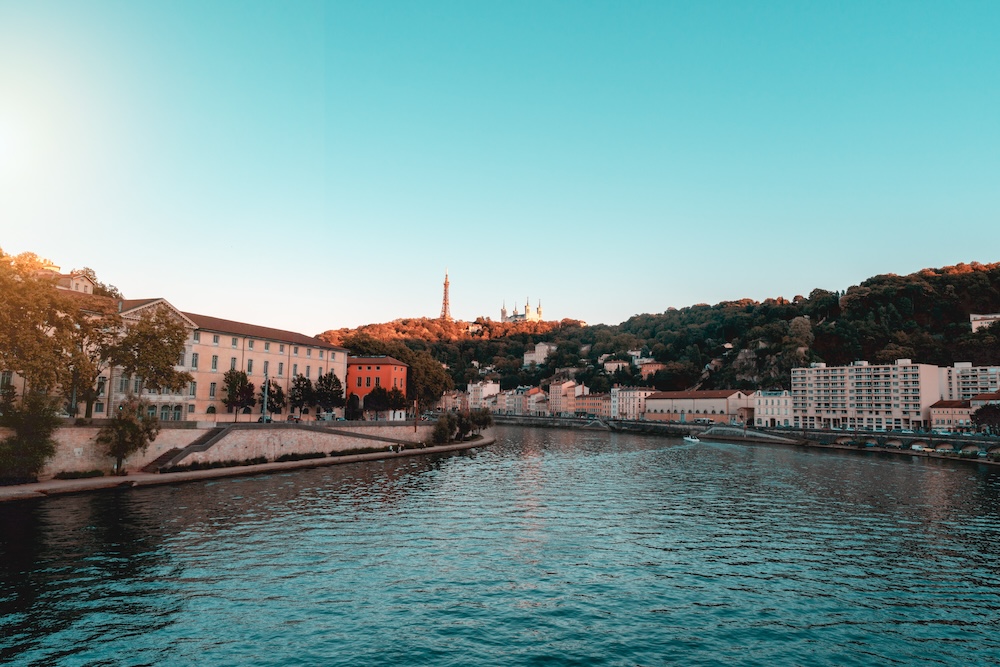 Vue panoramique sur les toits de Lyon au coucher de soleil avec la basilique Notre-Dame de Fourvière dominant la ville