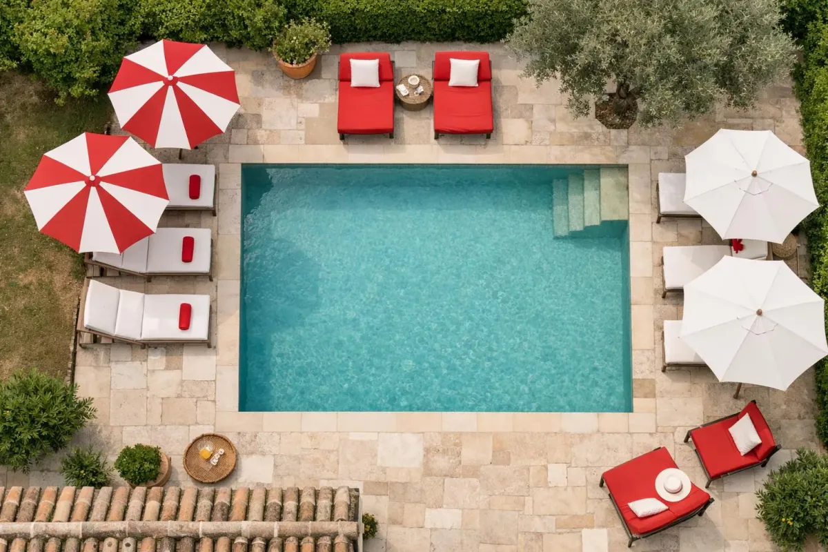 Une piscine extérieure entourée de parasols rouges et blancs et de chaises longues.