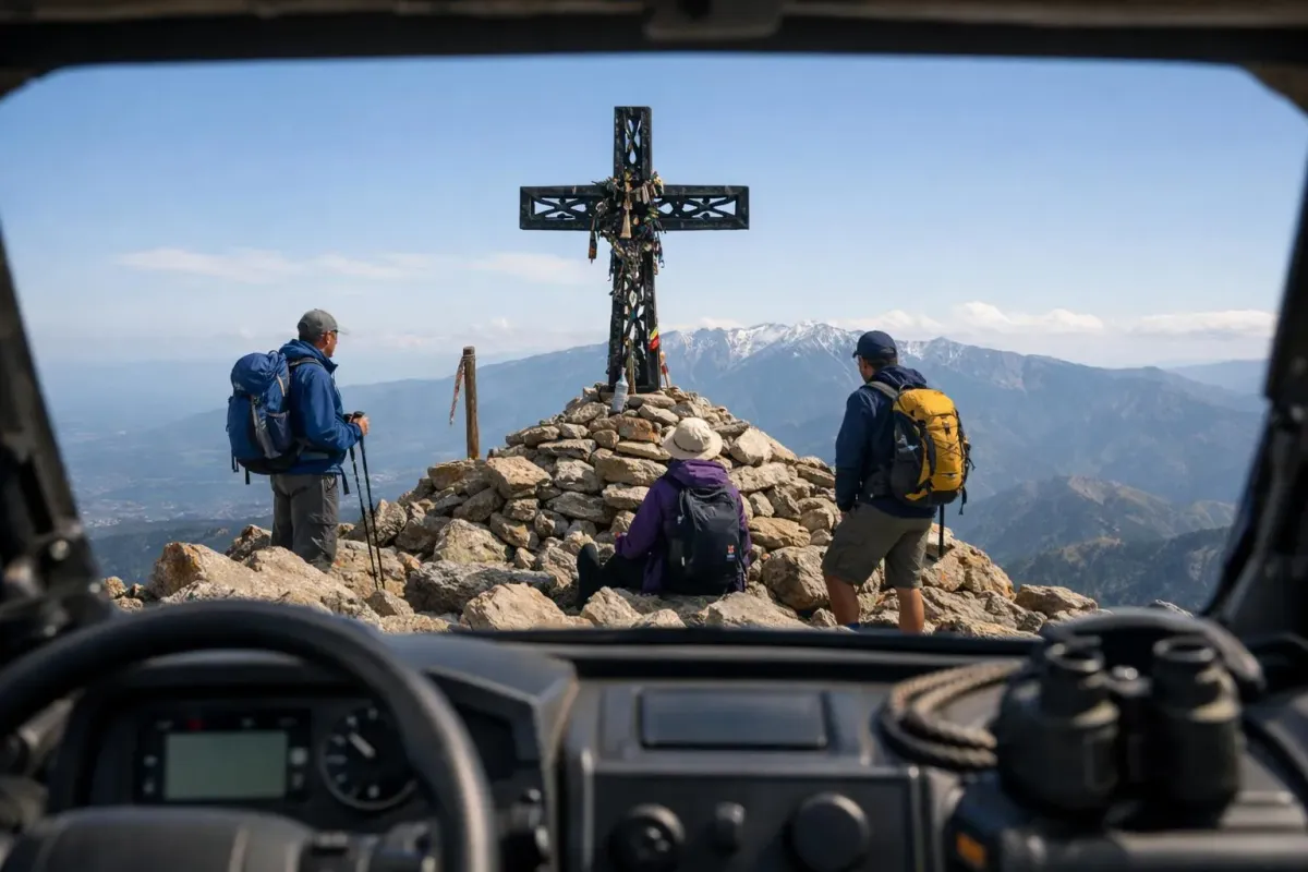 Randonneurs contemplant une croix sur une montagne enneigée.