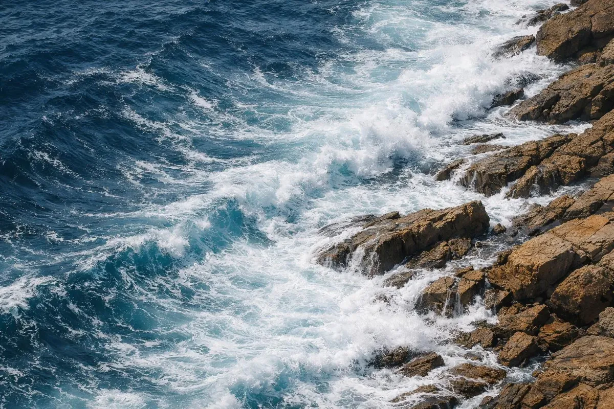 Vagues puissantes s'écrasant contre des rochers escarpés au bord de l'océan.