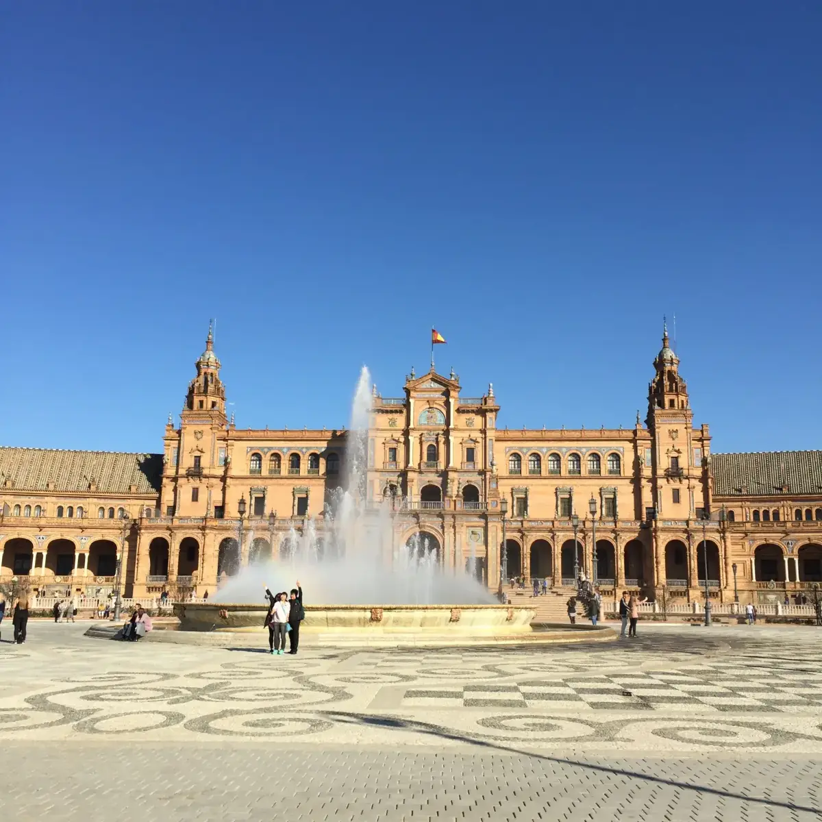Plaza de España de Séville avec sa fontaine centrale et son grand bâtiment sous un ciel bleu éclatant