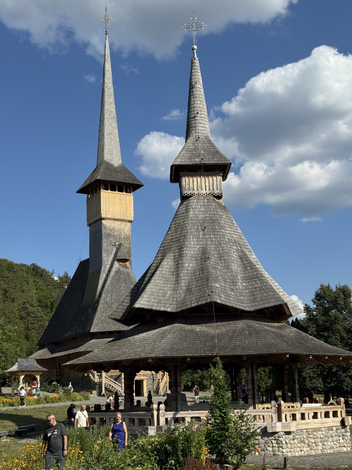 Église en bois à la flèche effilée et autel d'été du monastère de Bârsana sous un ciel bleu