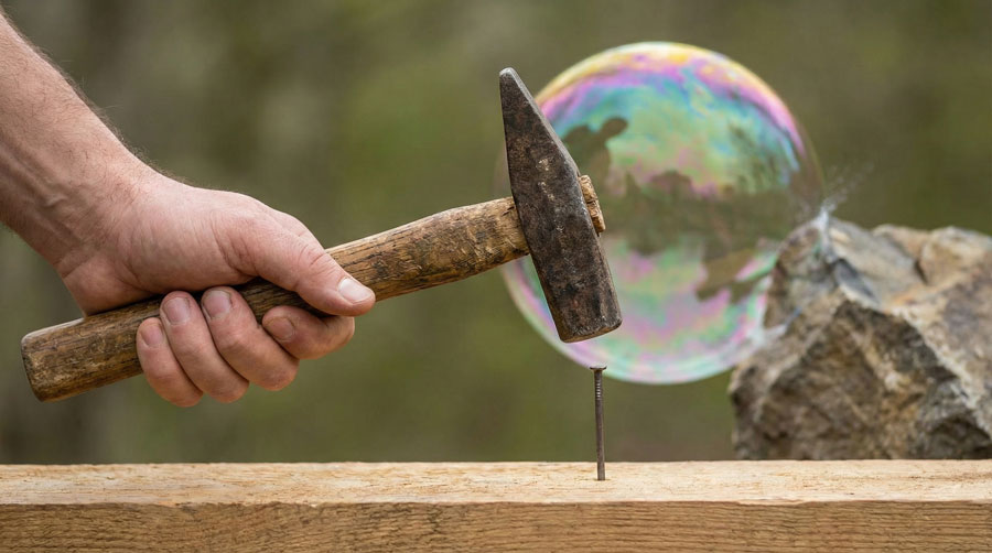 man houd hamer boven spijker die in een plank staat