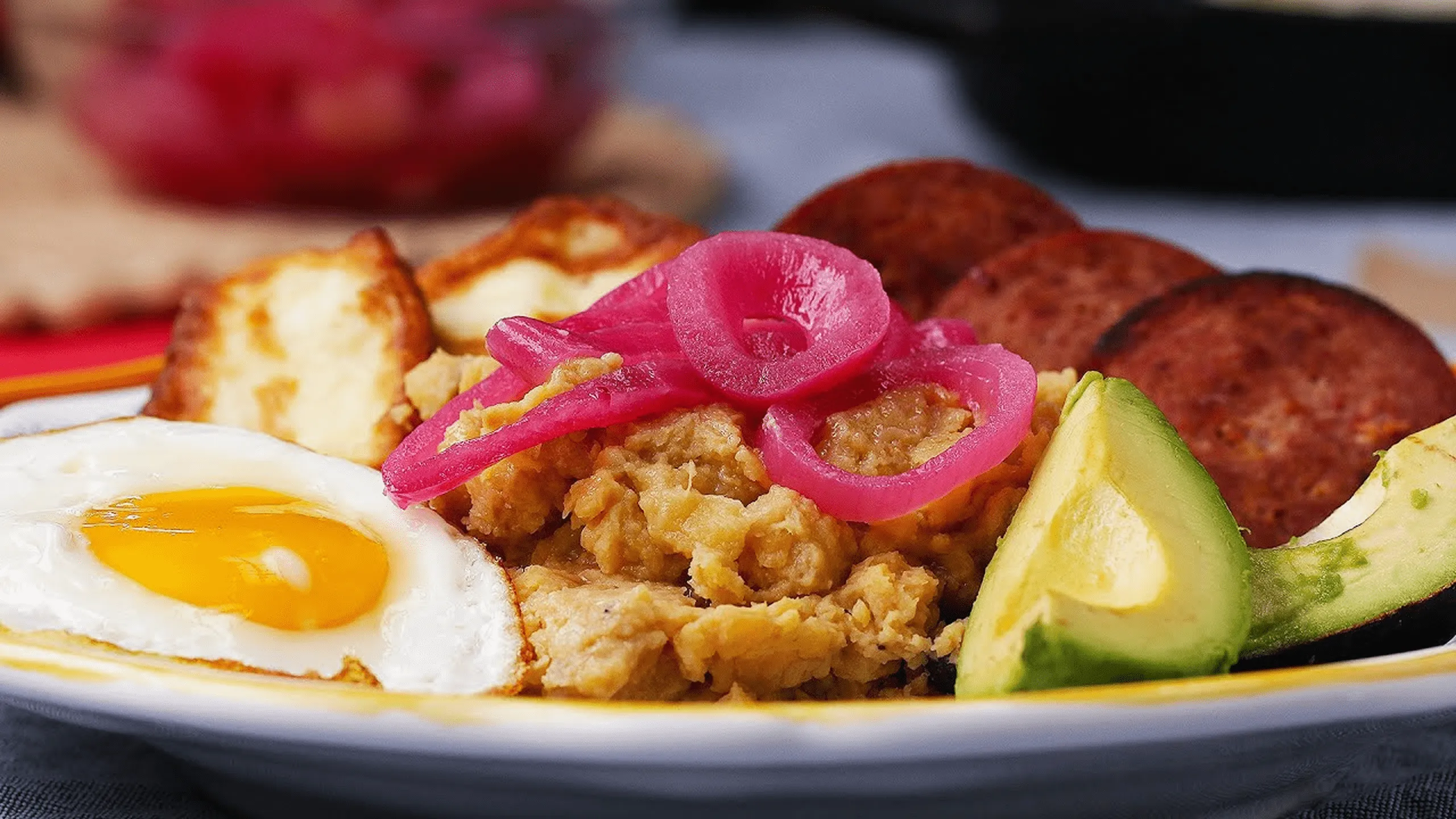 Screenshot of tres golpes with salami, fried cheese, avocado, red onions, and eggs served with mangú