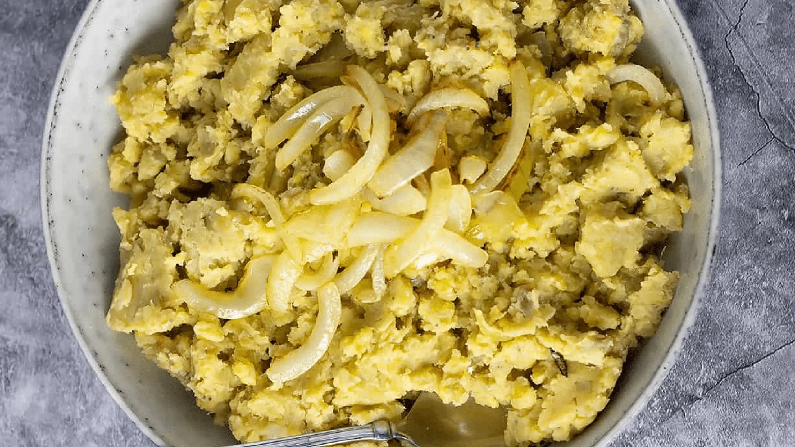 Screenshot of mashed plantains topped with caramelized onions.