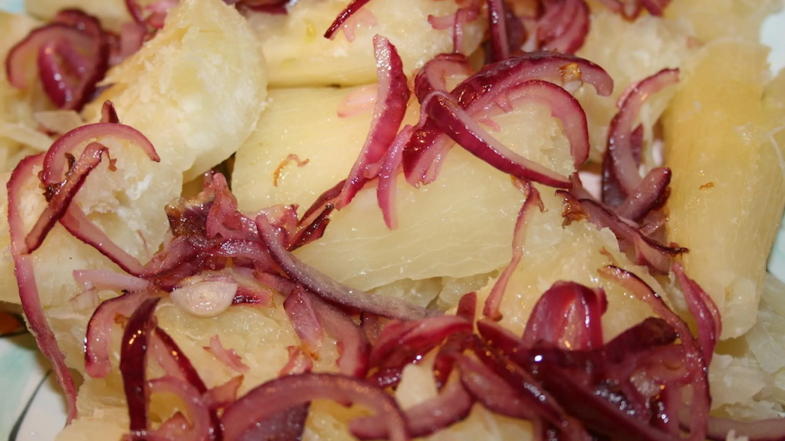 Screenshot of boiled yuca topped with caramelized red onions.