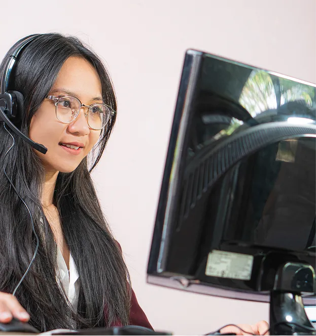 a woman in front of a computer and wearing a headset