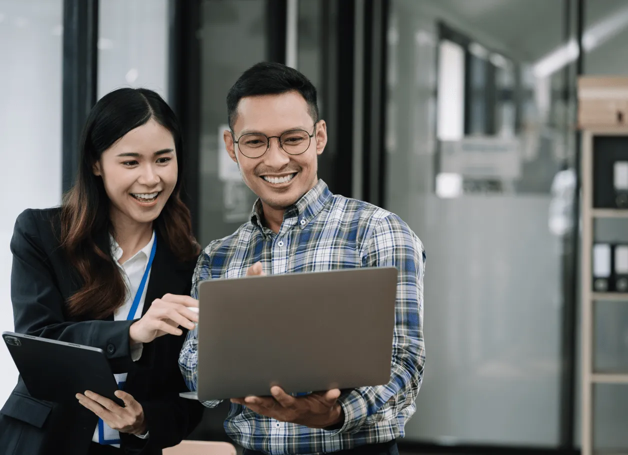 A man and a woman holding their laptop while discussing