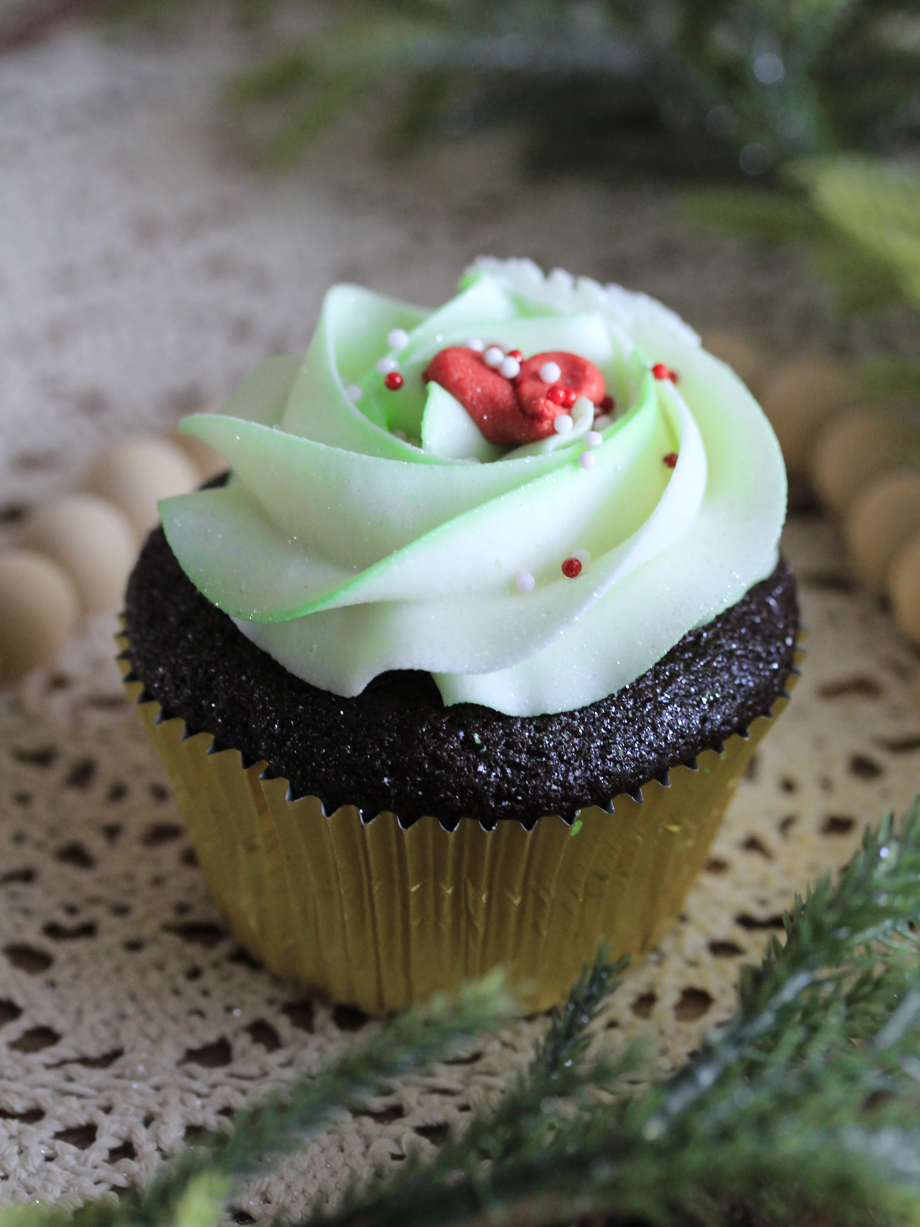 Close-up of custom chocolate cupcakes with white frosting and autumn leaf-shaped sprinkles in fall themed cupcakes liners.