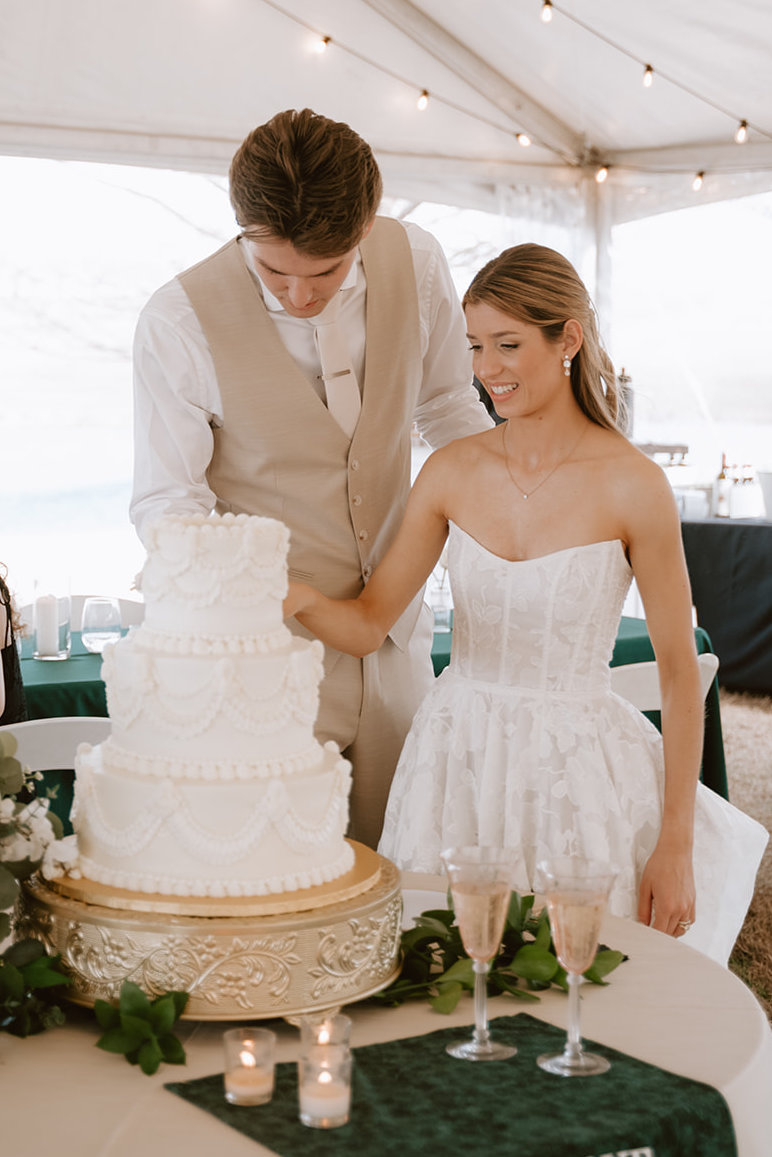 Beautiful bride and groom slicing a three-tier vintage lambeth style wedding cake at the wedding reception in Gunter, Texas. 