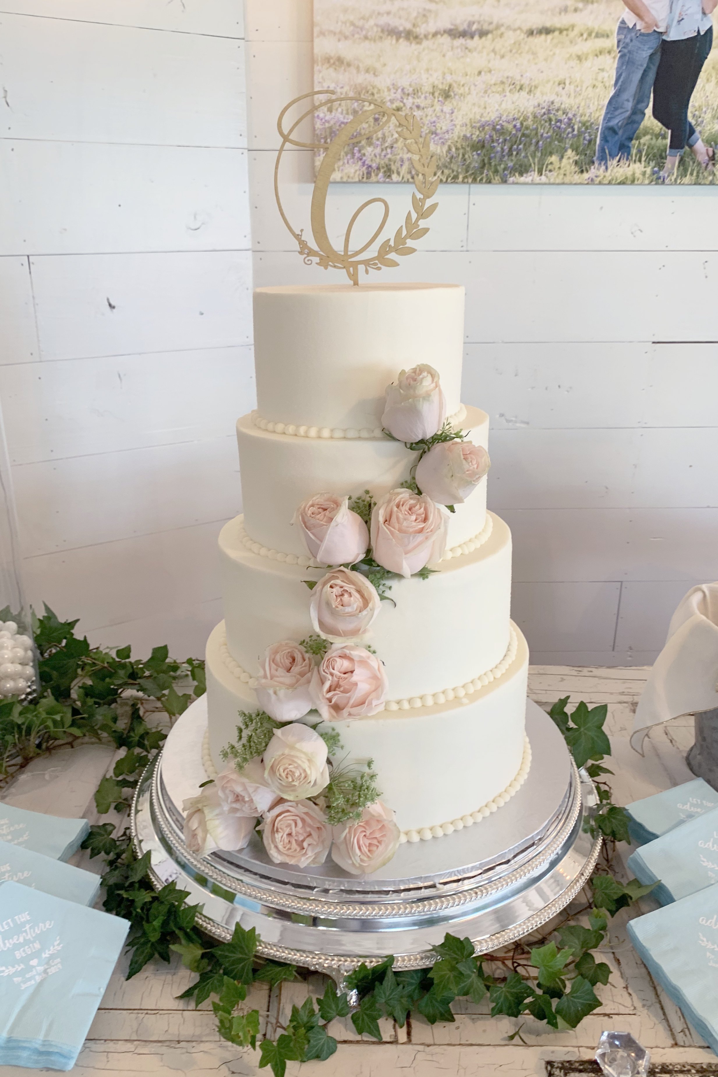 Four tier wedding cake with buttercream and fresh pink roses at Big Sky Event Venue in Royce City Texas.