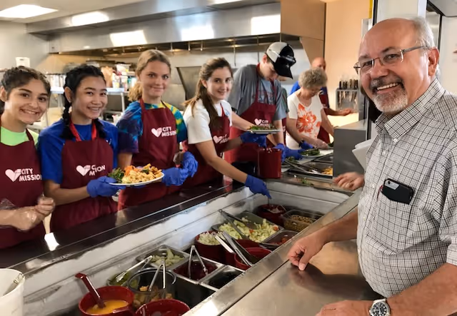 5 youthful volunteers in the cafeteria alongside CEO Dean Gartland
