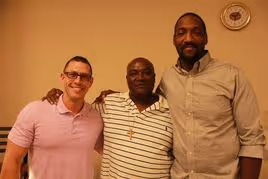 3 male City Mission Resident give a group hug