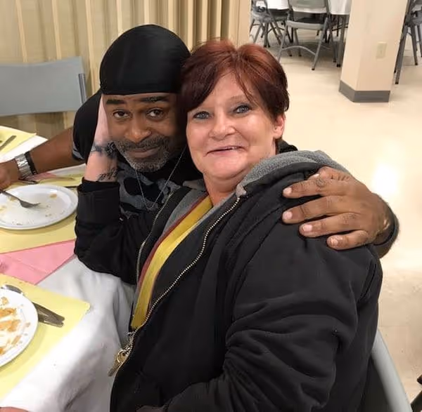 A female resident gives a big smile while sitting at a table in the cafeteria eating breakfast