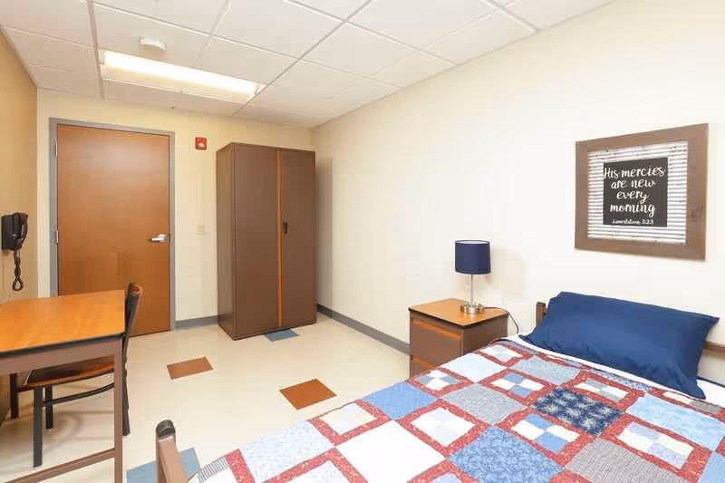 A veteran leans back against his bunk with a picture of American Marines raising the flag on Iwo Jima in the background at City Mission's Crabtree-Kovacicek Veterans House