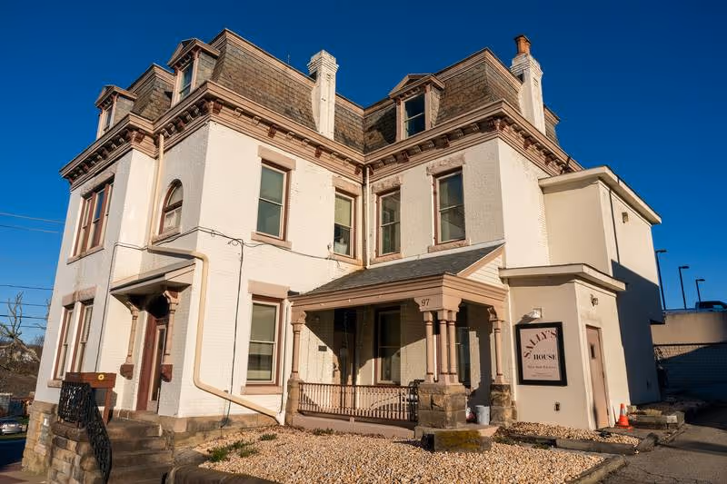 A veteran leans back against his bunk with a picture of American Marines raising the flag on Iwo Jima in the background at City Mission's Crabtree-Kovacicek Veterans House