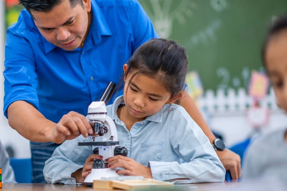 a teacher showing a child how to use a microscope