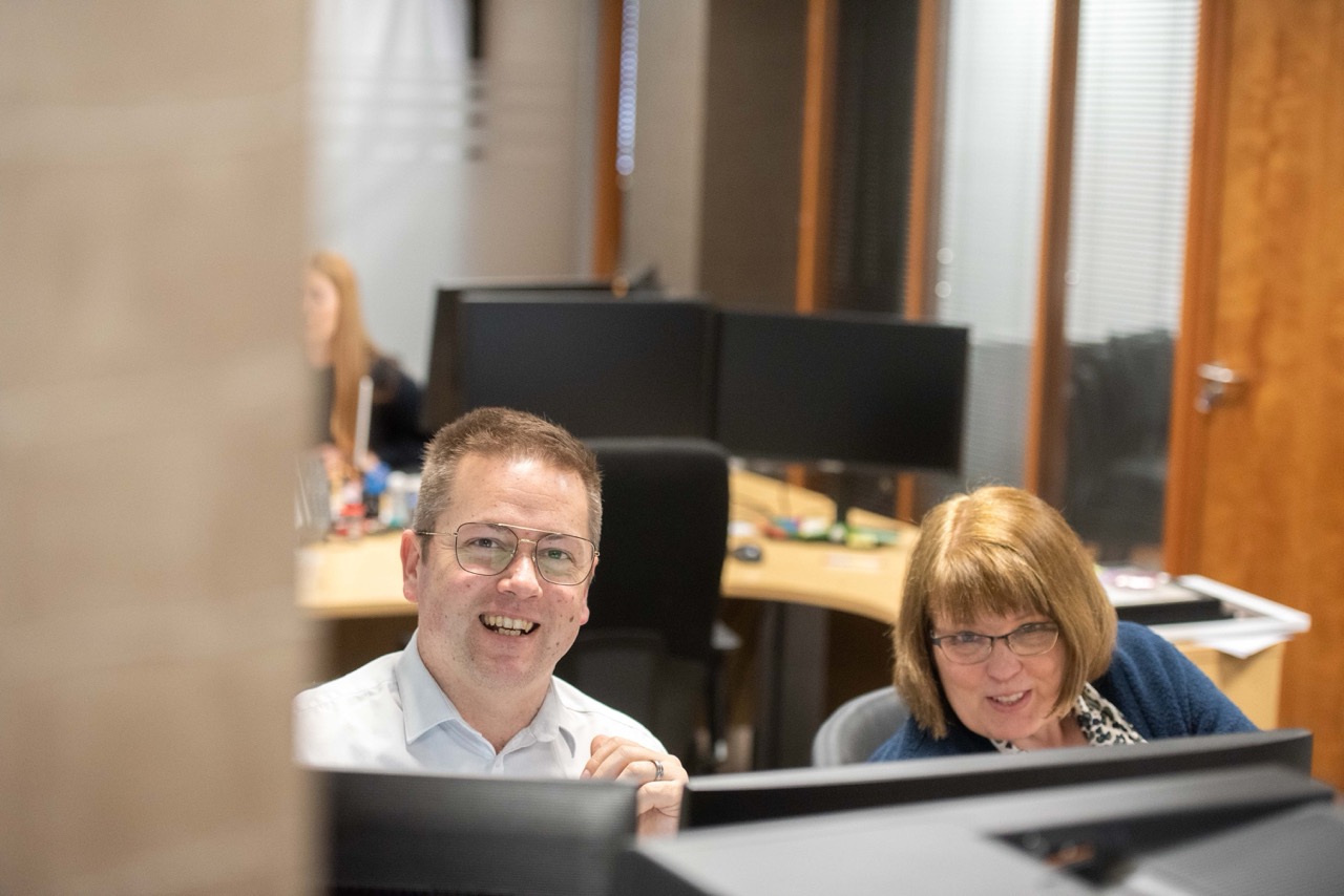 Two colleagues smiling from behind a desk