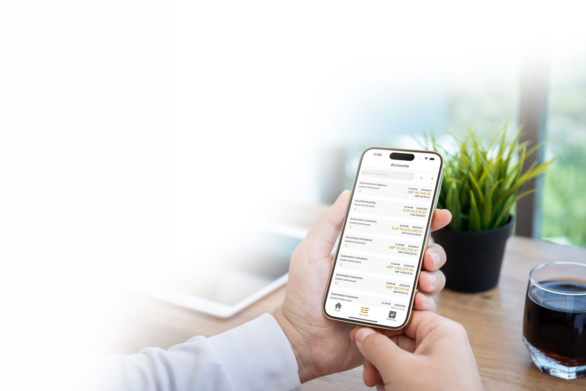 Person holding smartphone displaying financial accounts with balances in various currencies on screen.