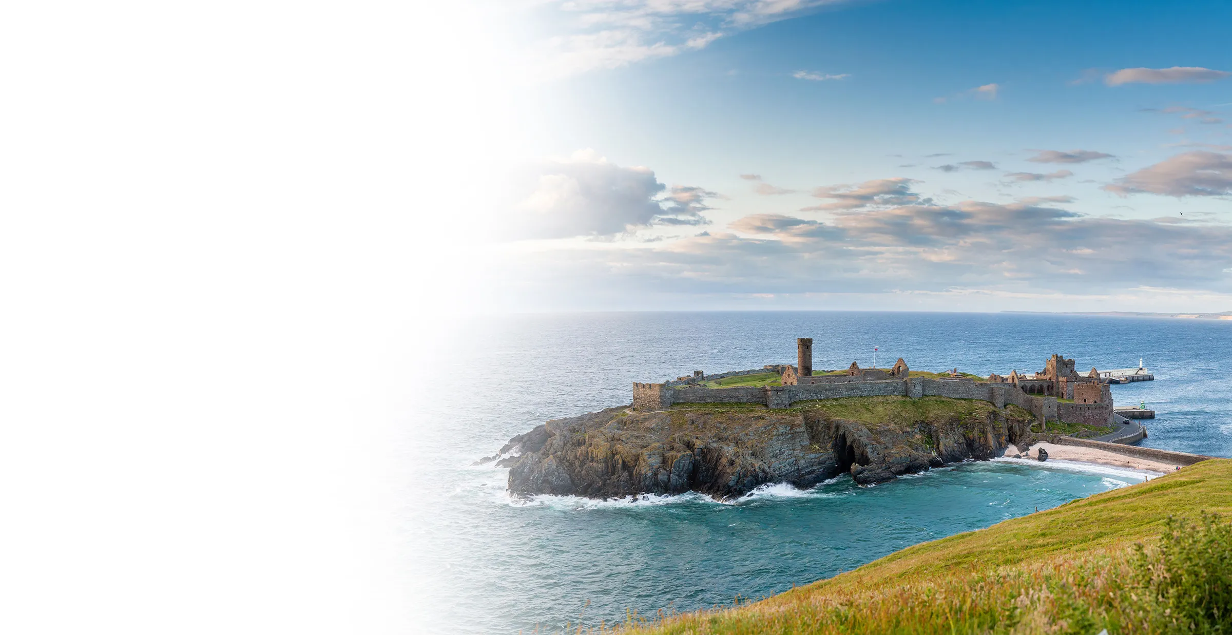 Stone castle ruins on rocky island surrounded by ocean under a partly cloudy sky.