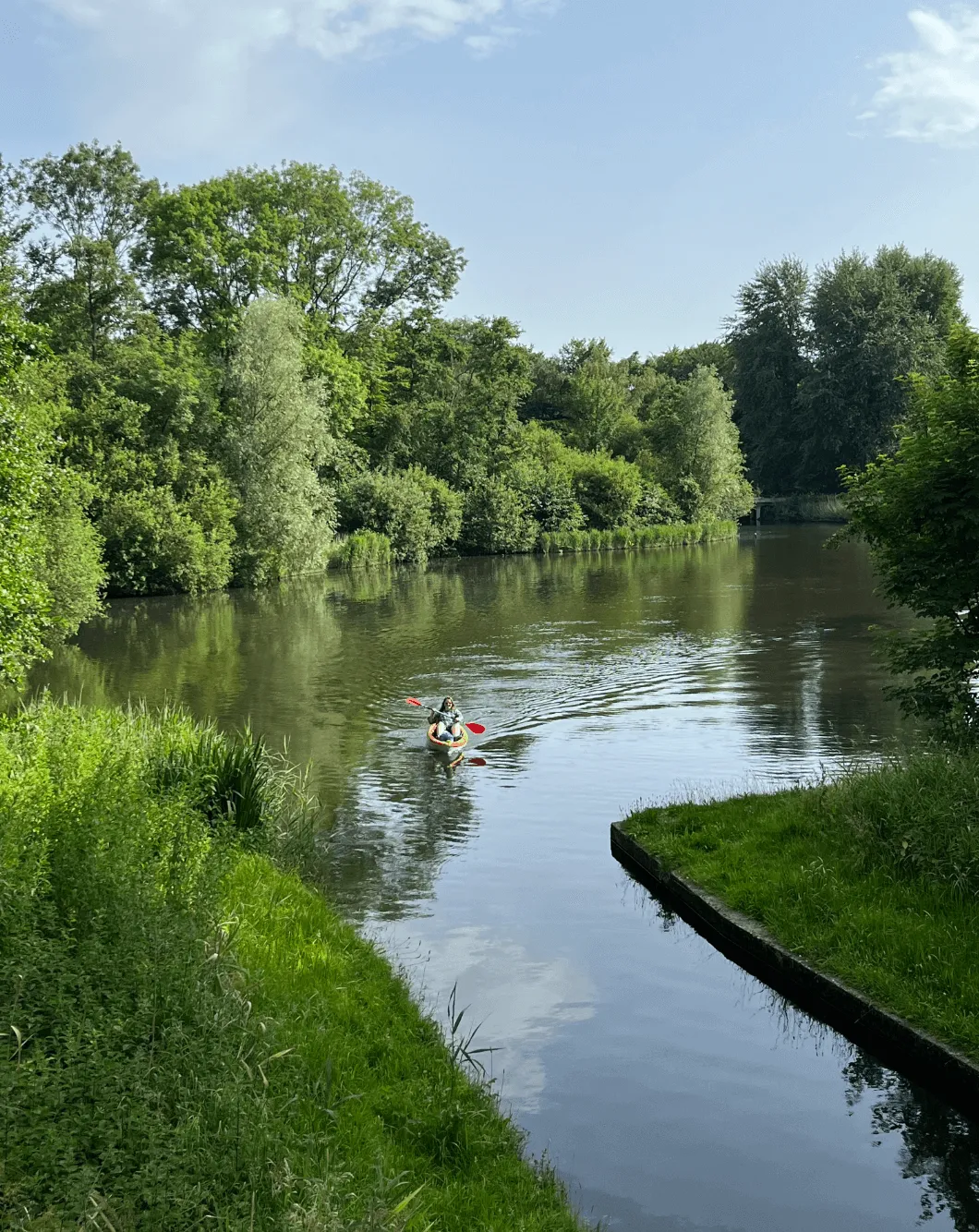 Lydia (our Content Lead) canoeing in a forest on an orange canoe