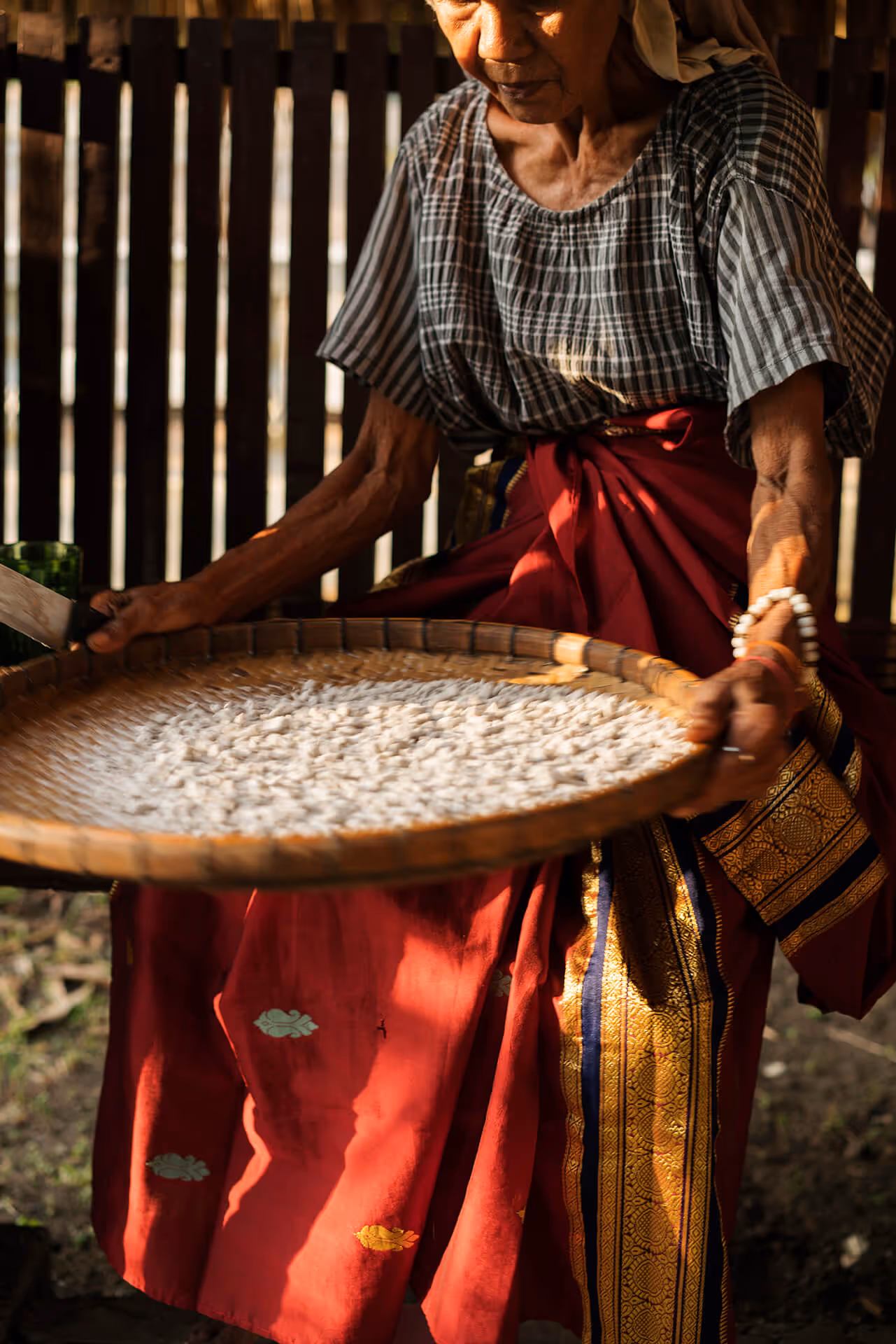 A woman sorts grains on a bilao in Maguindanao, photo by Sonny Thakur