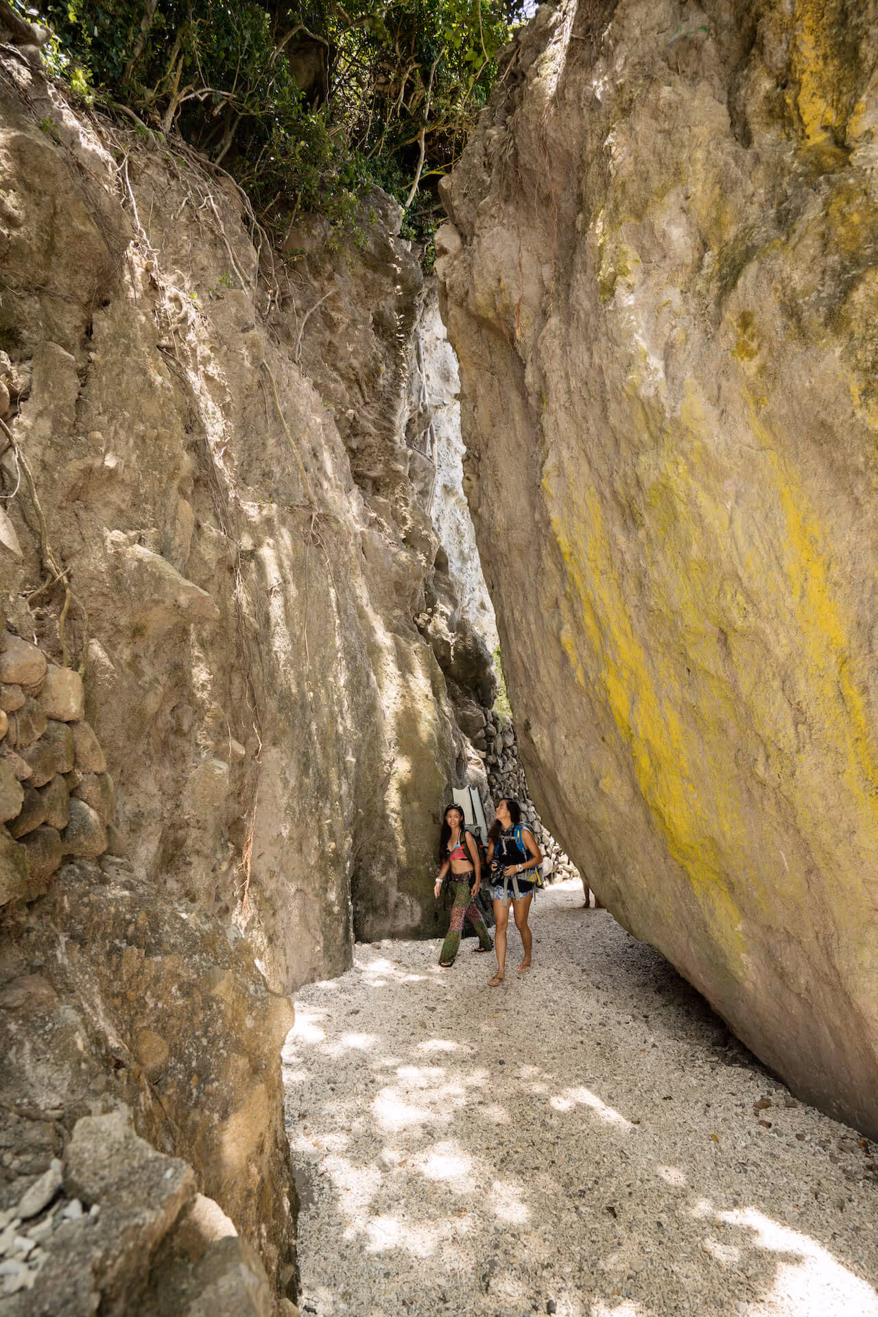 Tara Abrina and Carmen del Prado walk through a path between large rocks towards the dive site, photo by Sonny Thakur