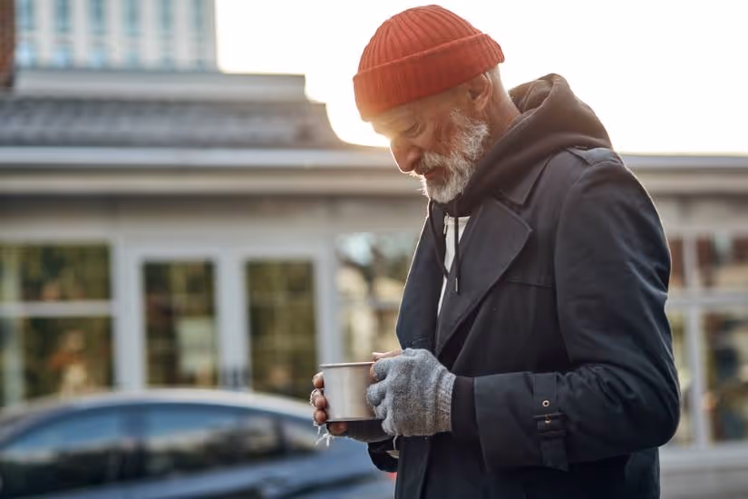 Homeless man looking at cup