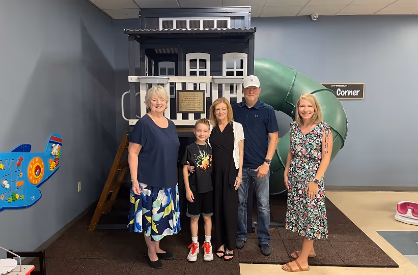 The Smydo family in front of the treehouse playset they donated.