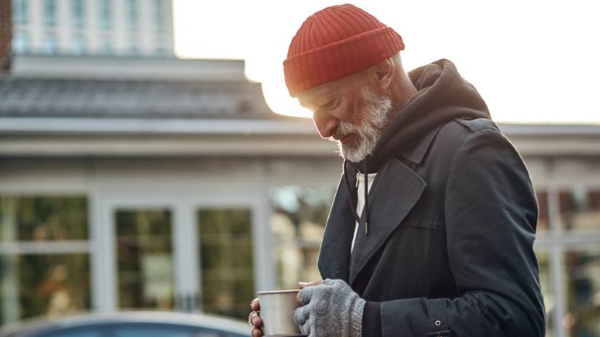 Homeless man looking at cup