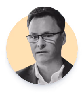 Hombre con gafas y chaqueta mirada hacia adelante sobre fondo amarillo claro.