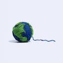 A blue ball of yarn with patches of green yarn; a model of earth.