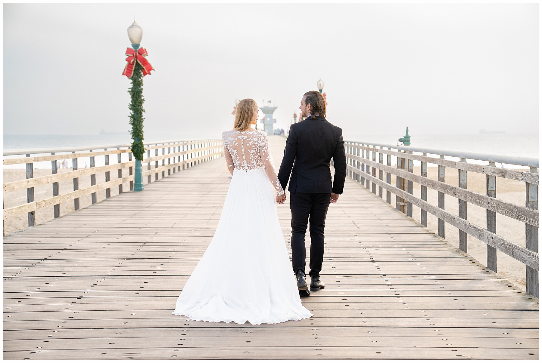 Romantic Seal Beach engagement portraits with a second-hand white dress, fitted white gown, and classic black suit. Coastal wedding photography with playful movement.