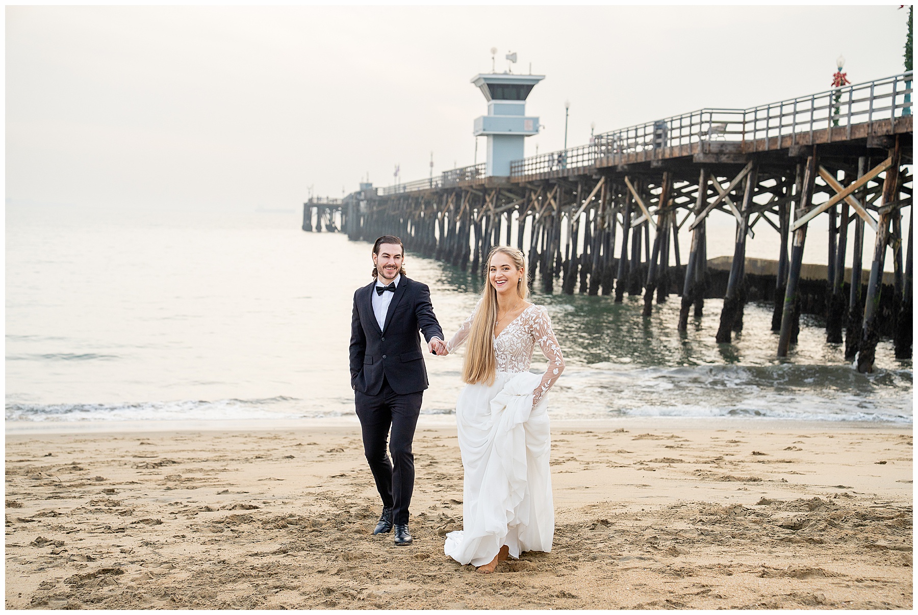 Romantic Seal Beach engagement portraits with a second-hand white dress, fitted white gown, and classic black suit. Coastal wedding photography with playful movement.