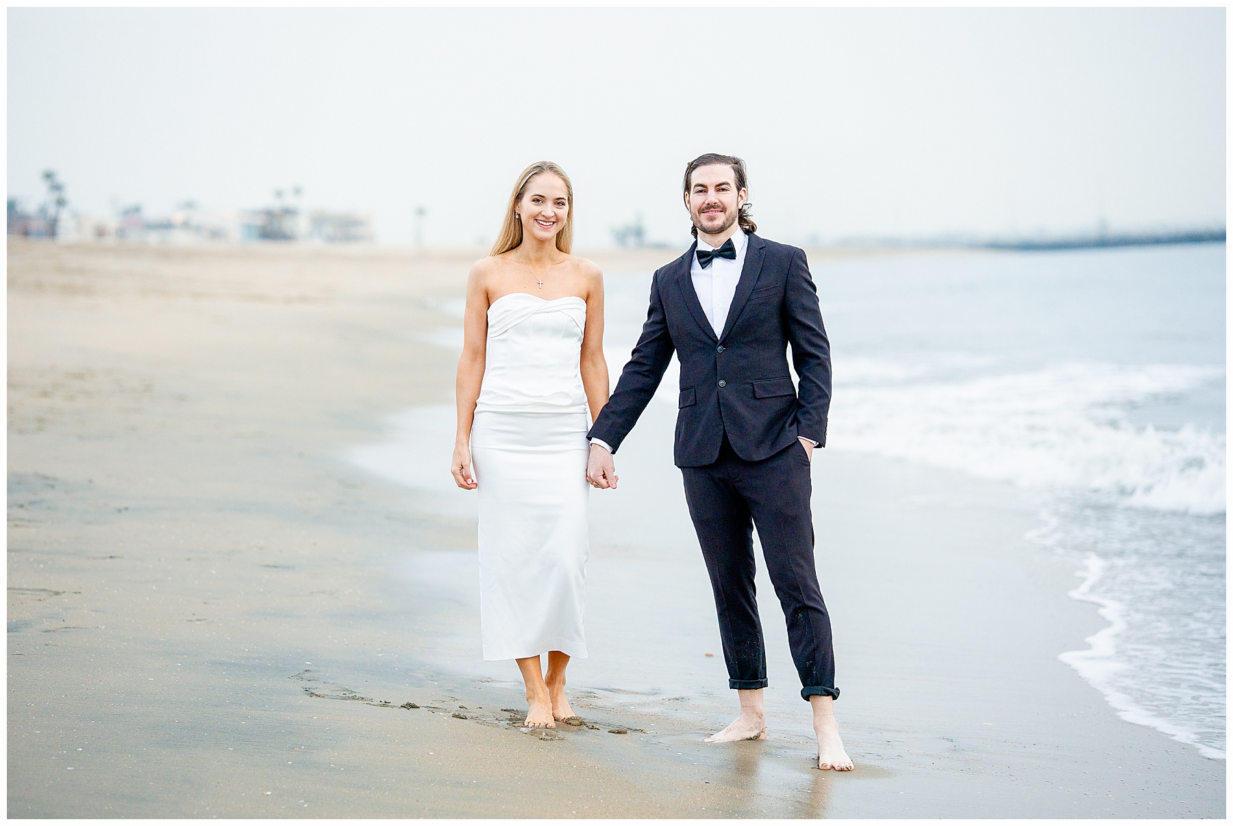 Romantic Seal Beach engagement portraits with a second-hand white dress, fitted white gown, and classic black suit. Coastal wedding photography with playful movement.
