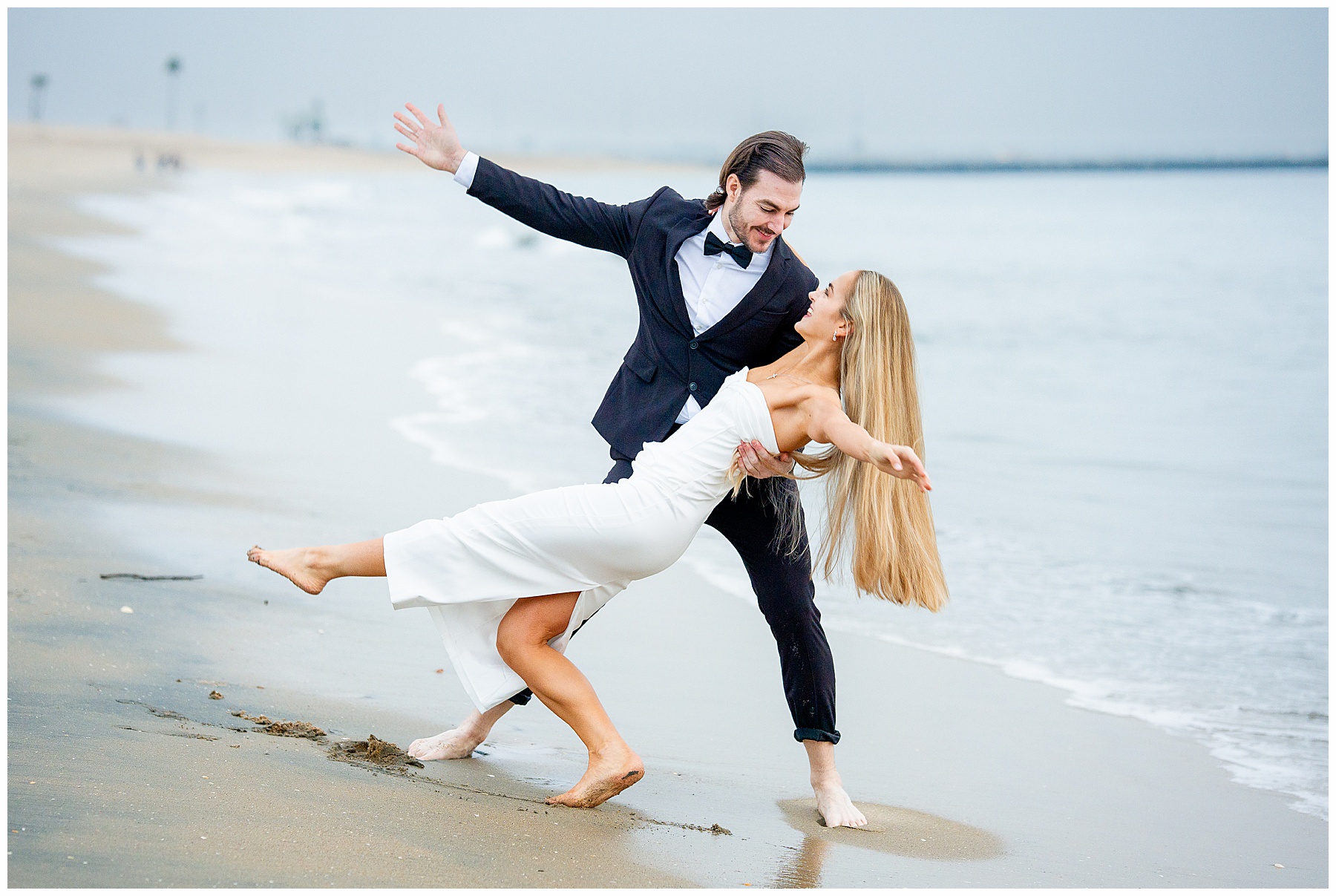 Romantic Seal Beach engagement portraits with a second-hand white dress, fitted white gown, and classic black suit. Coastal wedding photography with playful movement.