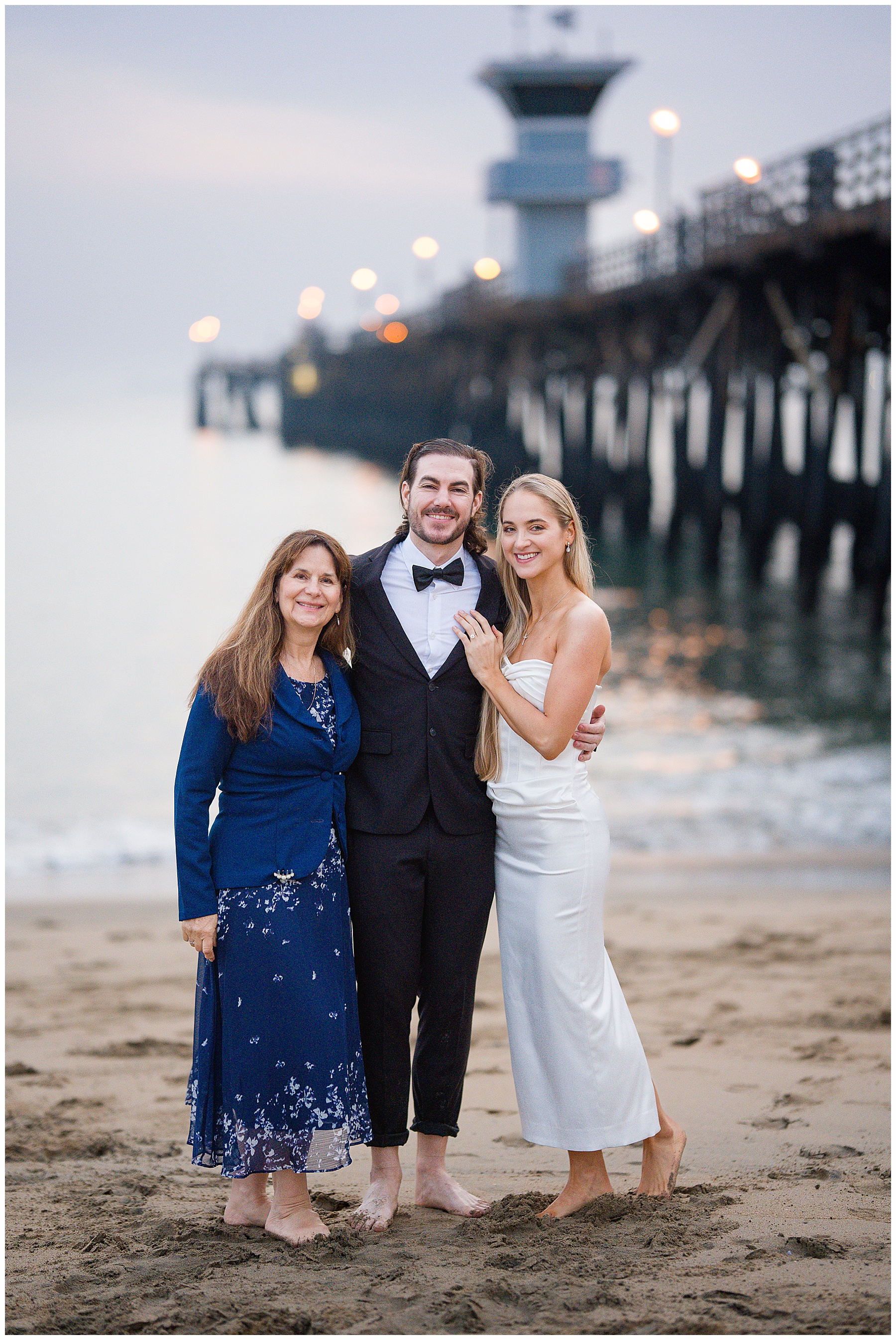 Romantic Seal Beach engagement portraits with a second-hand white dress, fitted white gown, and classic black suit. Coastal wedding photography with playful movement.