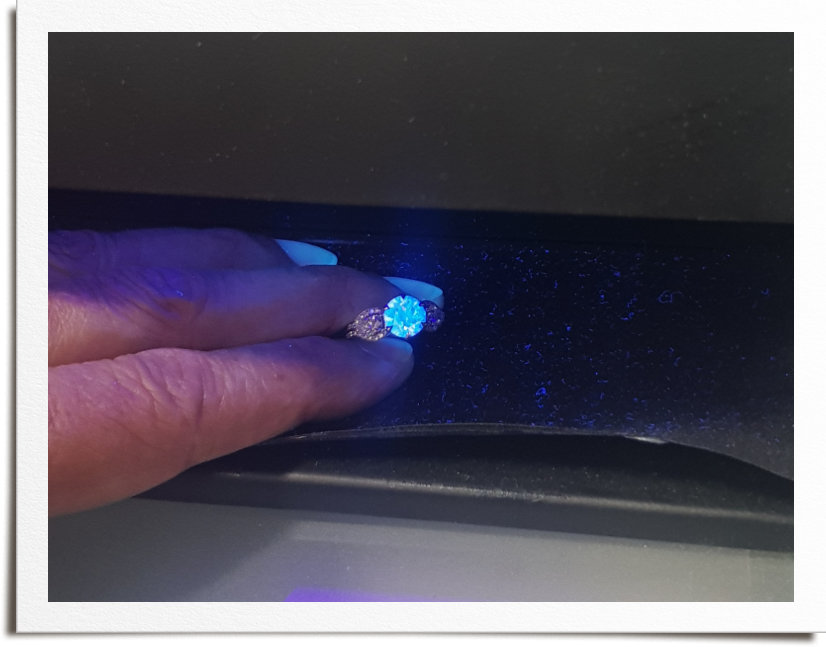 Image of diamond under UV light showing strong blue fluorescence. Side stones have no fluorescence.e