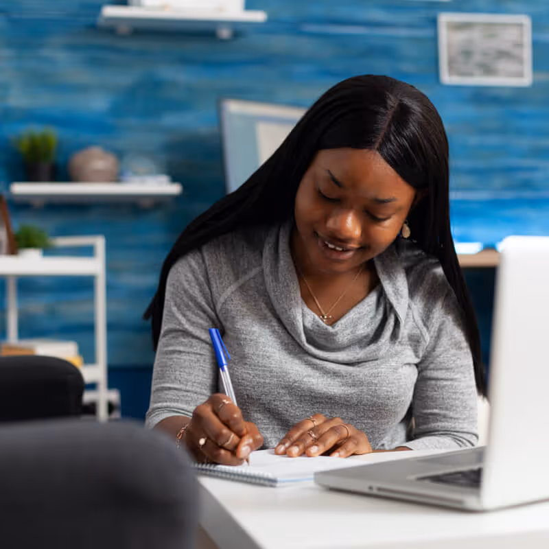 women watching the tscs webinar on laptop and taking notes