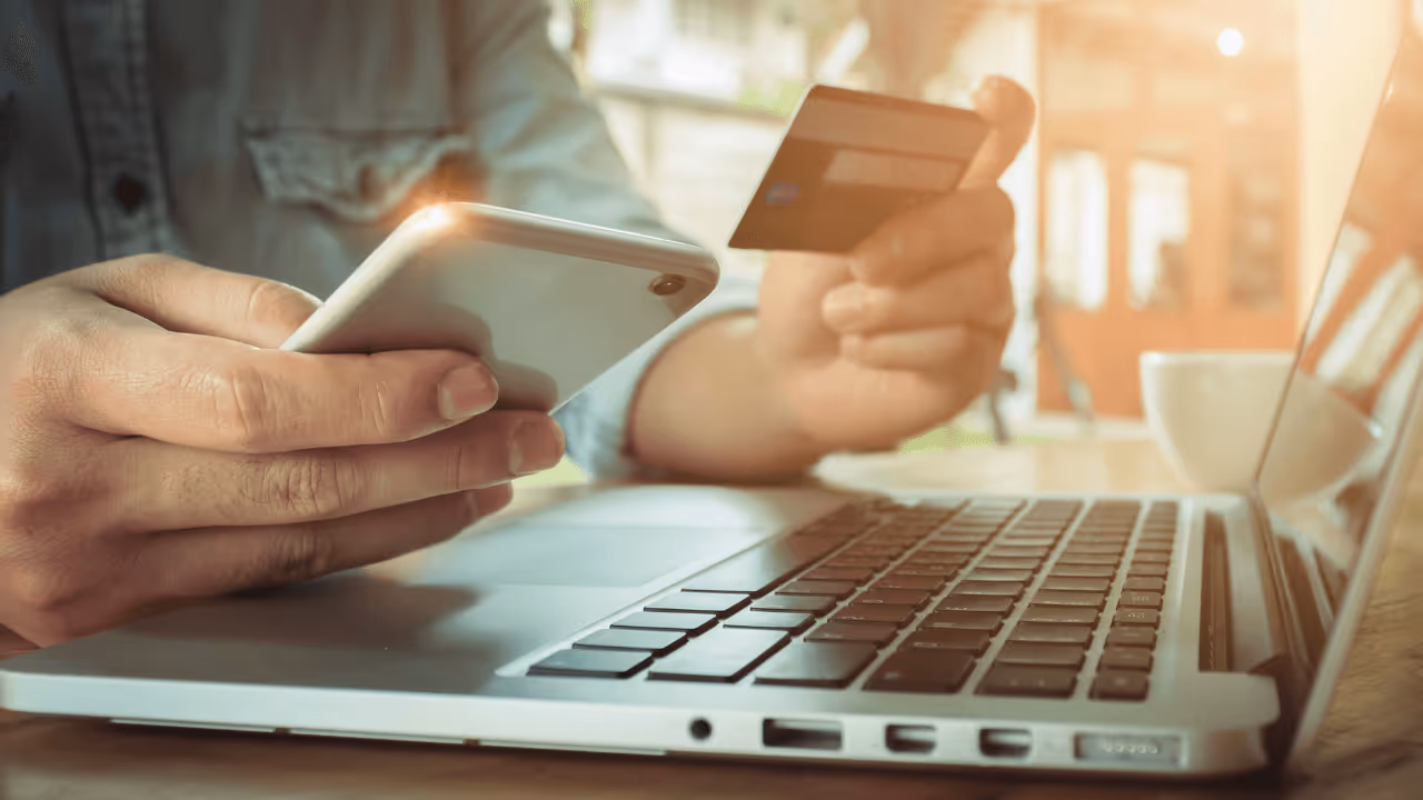 person using their phone and laptop to do a credit card transaction