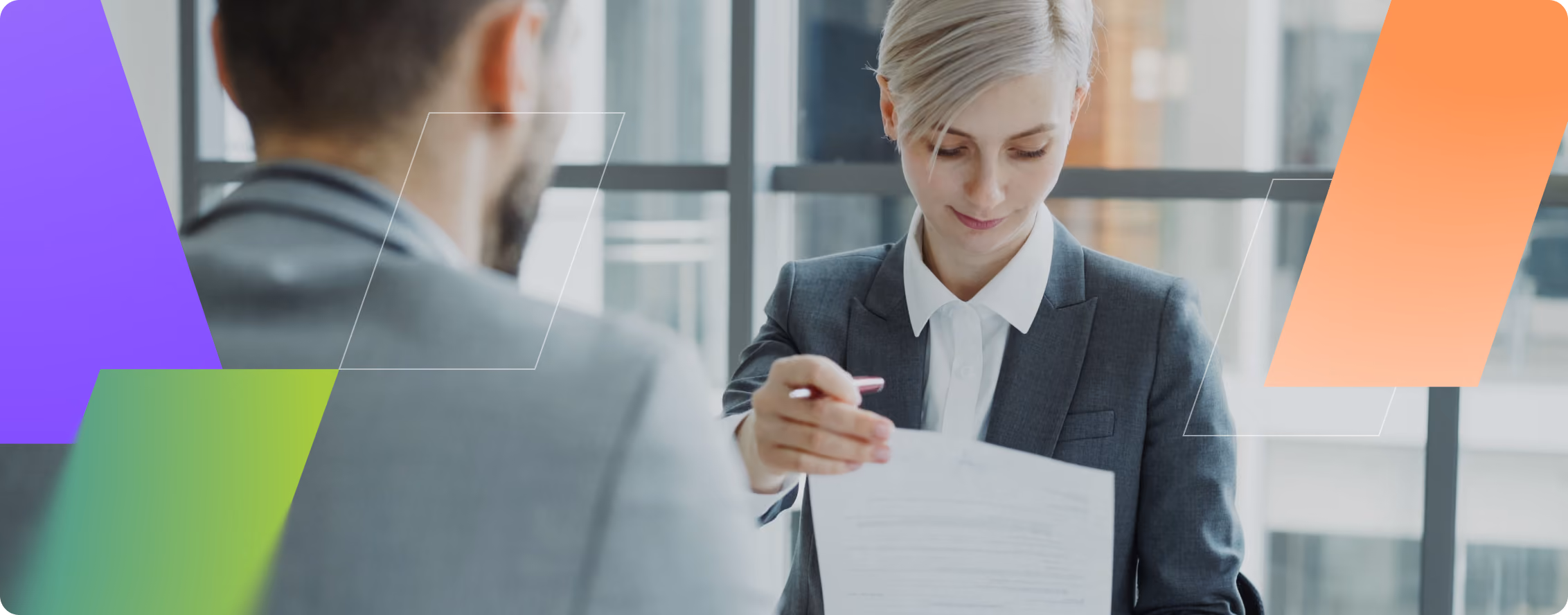 Businesswoman in a suit handing a document to a man in a suit during a meeting.