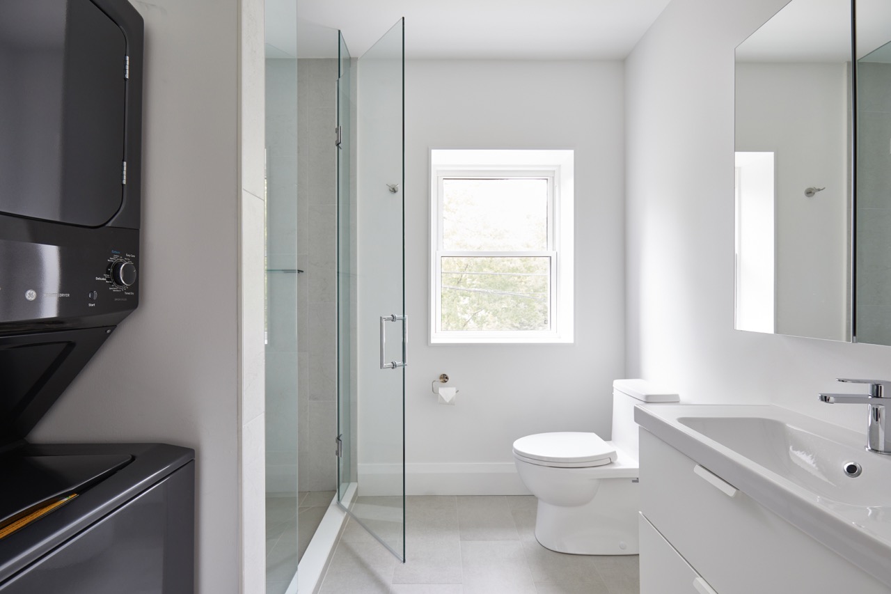 Annex Duplex: Waterfall quartz islands anchor each space, paired with full-height oak pantry walls, integrated stainless appliances, and a white subway tile backsplash