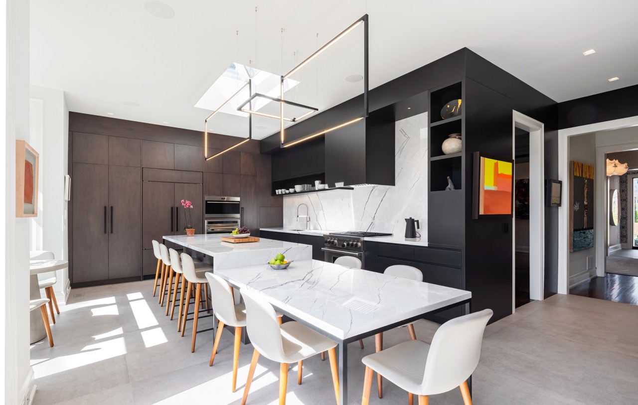 Stylish South Hill: This South Hill renovation is anchored by a dramatic kitchen that doubles as the dining room: a single waterfall marble island runs the length of the space, seating both stools and a full dining table beneath a run of skylights…