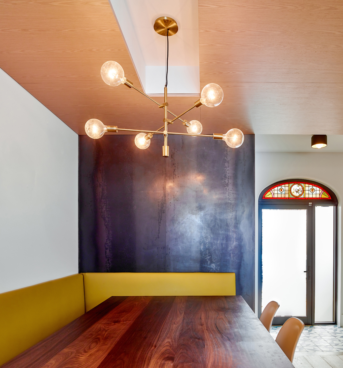 Roncesvalles Reno: The ground floor opens onto a cozy built-in banquette with a wood ceiling that wraps down one wall, adding warmth and richness to a clean interior