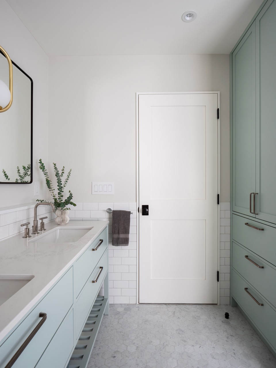 Rusholme Restored: The adjoining kitchen goes moody with navy blue cabinetry, brass dome pendants, and a waterfall island with seating for the whole family