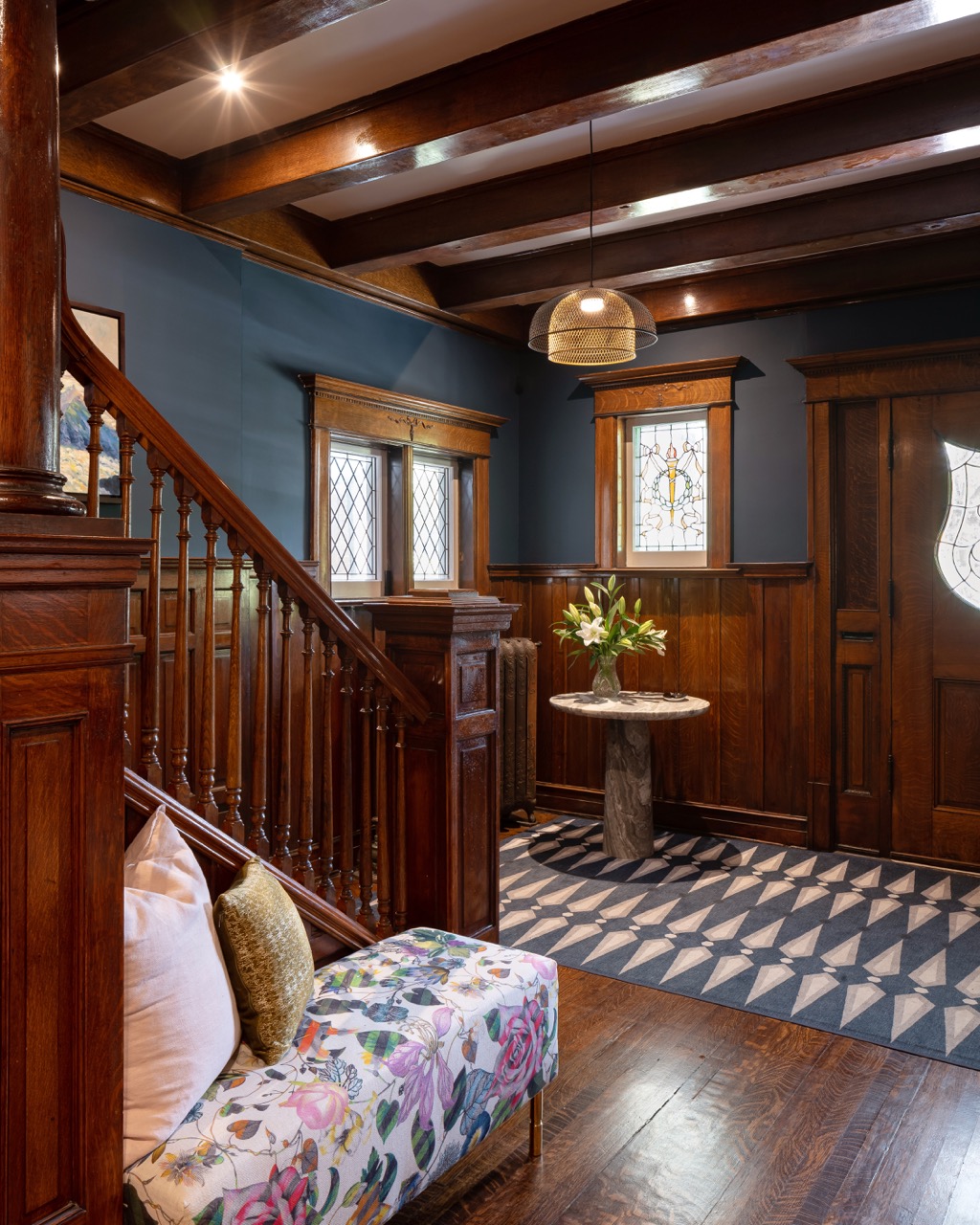 Rusholme Restored: The adjoining kitchen goes moody with navy blue cabinetry, brass dome pendants, and a waterfall island with seating for the whole family