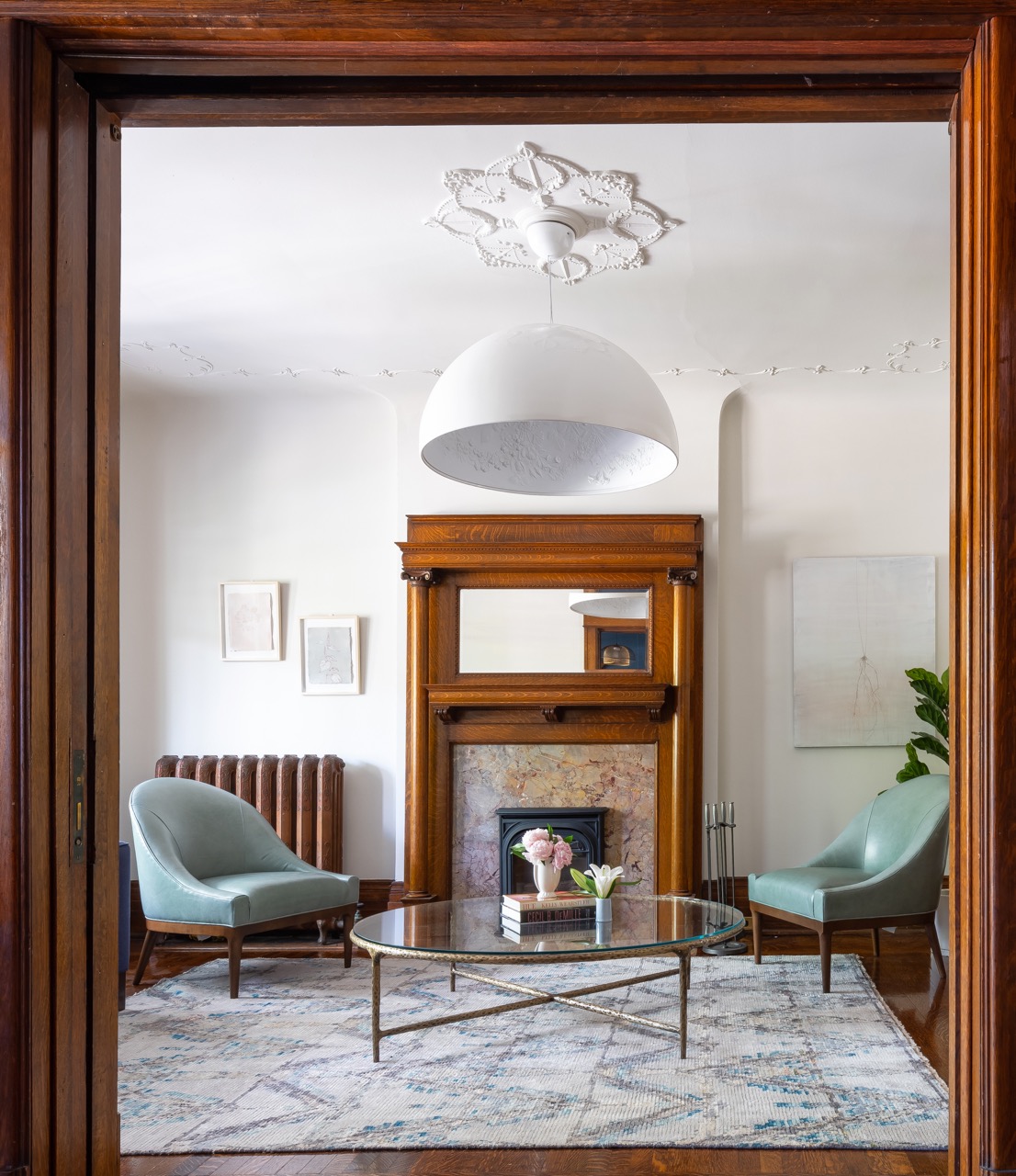 Rusholme Restored: The adjoining kitchen goes moody with navy blue cabinetry, brass dome pendants, and a waterfall island with seating for the whole family