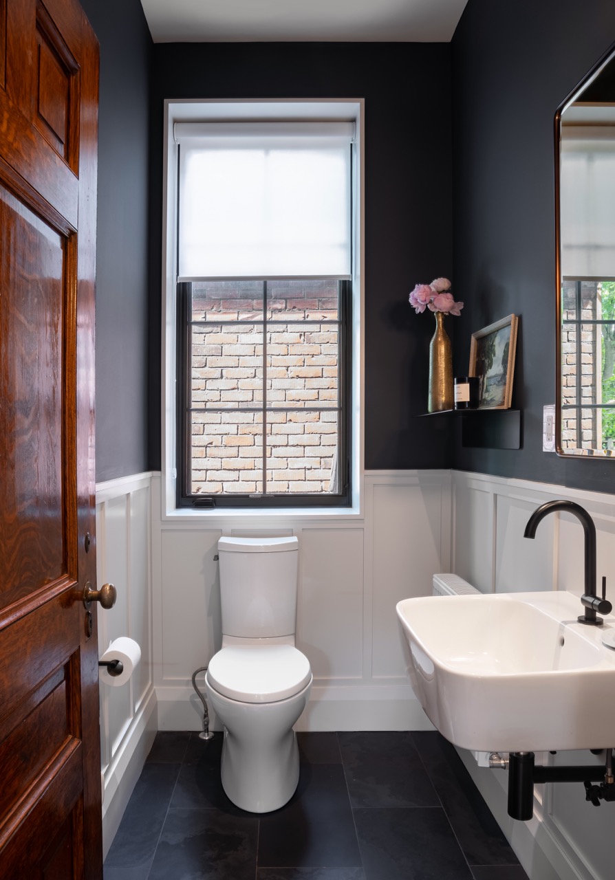 Rusholme Restored: The adjoining kitchen goes moody with navy blue cabinetry, brass dome pendants, and a waterfall island with seating for the whole family