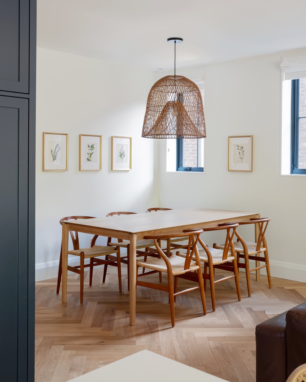Rusholme Restored: The adjoining kitchen goes moody with navy blue cabinetry, brass dome pendants, and a waterfall island with seating for the whole family